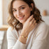 Smiling woman in a cream sweater shows off a Red Evil Eye Charm Bracelet with red accents, worn as a stylish protective talisman.